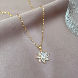Close-up of titanium gold flower pendant necklace with cubic zirconia on soft fabric