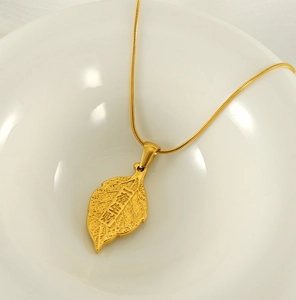 Detailed view of leaf pendant with engraved lucky text on gold snake chain necklace