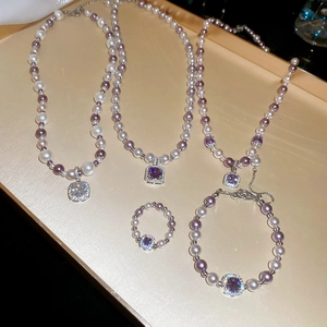 Flat lay of vintage style pearl jewelry set with square purple zircon pendants on a tray