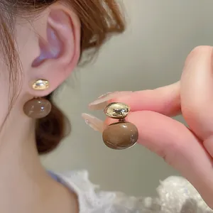 Boucles d'oreilles ovales plaquées or avec perles marron portées par mannequin