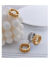Macro view of wide gear-shaped titanium steel rings in gold and silver finishes