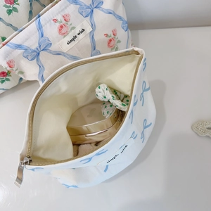 Détail de la trousse à maquillage avec roses roses, nœuds bleus et étiquette simple