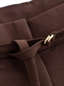 Dettaglio dei pantaloni a vita alta con cintura in tessuto e fibbia in metallo oro