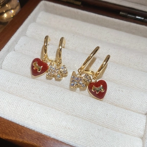 Macro view of gold puppy earrings with red enamel heart and sparkling zircon details