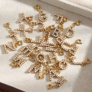 Detailed macro view of 18K gold plated letter pendants with white pearls and spring clasps