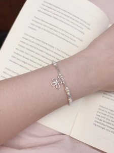 Detail of freshwater pearl bracelet with silver flower pendant on a model wrist