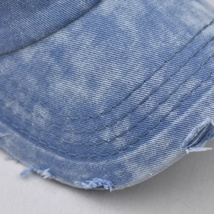 Close-up of blue washed denim brim featuring detailed stitching and distressed frayed edges