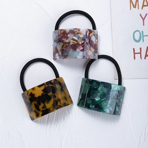 Three acetate ponytail holders in tortoise shell and marble patterns on white background