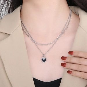 Close-up of double-layer silver titanium necklace with a black heart pendant on a model