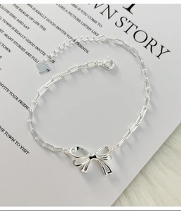 Detail of silver S925 bow-knot chain bracelet with adjustable lobster clasp and heart charm