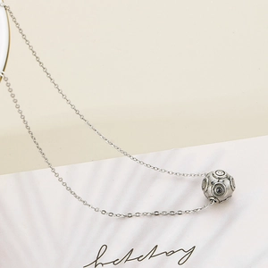 Macro shot of silver ball pendant with vintage concentric circles on stainless steel chain
