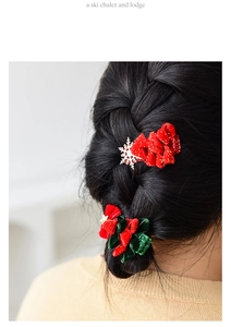 Close-up of red and green Christmas bow hair clips with snowflake details on a braided hairstyle