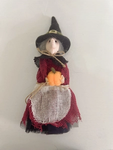 Detail of a handmade red burlap witch hanging doll with orange pumpkin for Halloween
