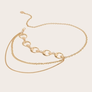 Detail of layered gold metal waist chain with hollow moon and star charms on beige base
