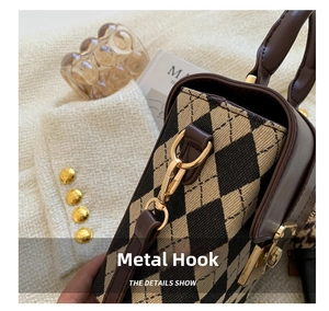 Detail shot of vintage style handbag featuring gold hardware hooks and leather stitching