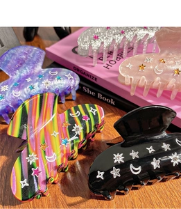 Detail of four hair claws with stars, moons and rhinestones on a wooden desk with books