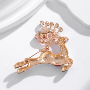 Golden Christmas reindeer brooch with red enamel and rhinestones on textured background