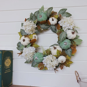 Autumn wreath with white pumpkins, hydrangeas and maple leaves on white wooden background