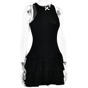 Détail de mini robe noire côtelée avec petit nœud blanc et ourlet à volants étagés