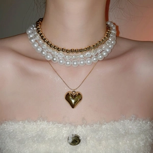Ensemble de colliers superposés en perles baroques et dorées avec pendentif en cœur