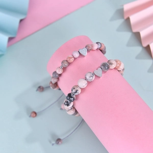 Close-up of pink zebra stone beaded bracelets with silver heart charm on display stand