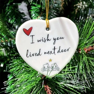 White heart ceramic ornament with 'I wish you lived next door' text on a Christmas tree