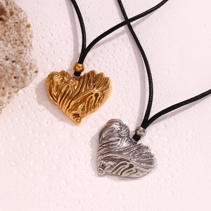 Detail of gold and silver heart pendants with lava texture on black cord necklaces