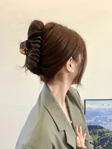 Detail view of large tortoiseshell pumpkin hair claw clip showing a secure grip on styled hair