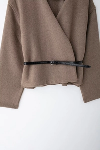 Détail d'une veste portefeuille marron en laine avec ceinture fine en cuir noir