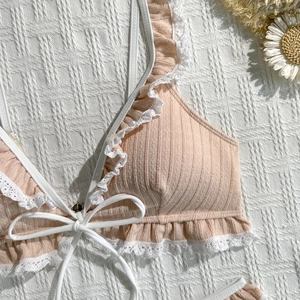 Close-up of pink ribbed bikini top with white lace trim, ruffles and front tie detailing