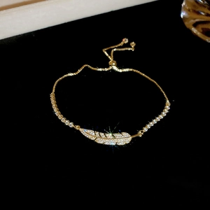 Macro shot of gold feather bracelet featuring pave-set cubic zirconia and sliding clasp