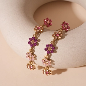 Vue détaillée de longues boucles d'oreilles fleurs en or avec cristaux colorés
