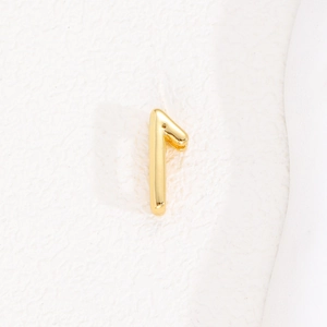 Macro shot of gold-plated number 1 earring charm with a high-polished metallic finish