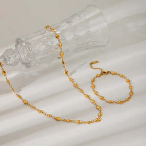 Detail von 18K Goldstern und Herzanhängern an einem zarten Halsketten- und Armbandset