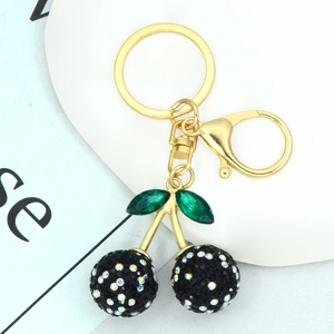 Close-up of cherry keychain with black rhinestones and green crystal leaves on gold link