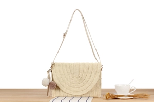 Detail of paper rope woven shoulder bag featuring tiered textures and fluffy pompom charm