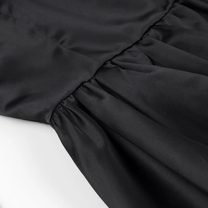 Gros plan sur les plis froncés et la texture du tissu à la taille de la robe noire