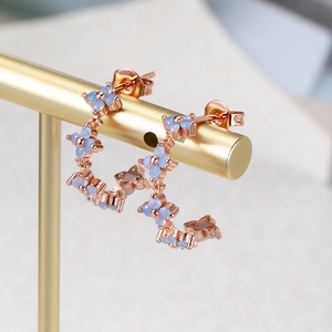 Macro shot of rose gold flower cluster C-shaped earrings with blue zircon stones