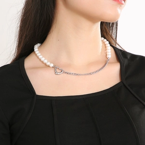 Detail of pearl and cuban link necklace with heart pendant shown on model