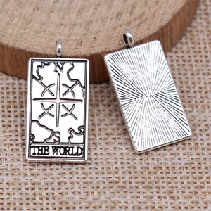 Macro view of vintage silver The World tarot card pendant on rustic wood and linen