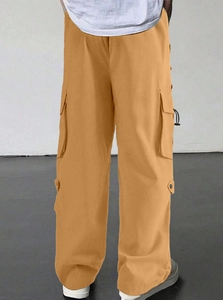 Detail of yellow parachute cargo pants featuring side large pockets and loose straight cut