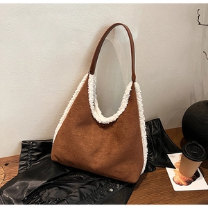 Close-up of a brown suede tote bag with white plush trim on a black leather jacket