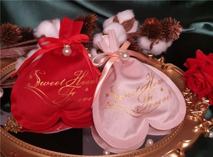 Velvet heart-shaped gift bags with pearls and bows on a premium golden tray
