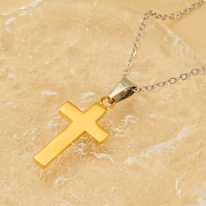 Detailed close-up of a two-tone 18K gold and silver cross necklace on ice texture surface