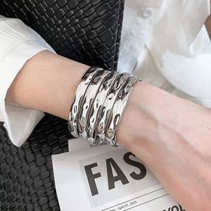 Polished silver layered cuff bracelets with hammered texture on a model's wrist