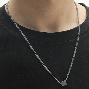 Minimalist silver cube pendant necklace with Cuban chain for men on black fabric