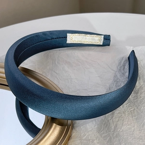 Detail of blue satin padded headband resting on gold frame with professional lighting