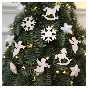 White glittery snowflake and angel ornaments decorating a green Christmas tree with warm lights