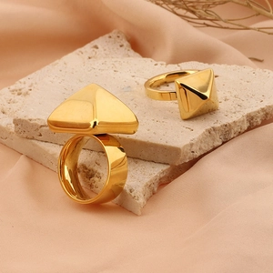 Set di anelli a piramide in acciaio al titanio placcato oro 18k su pietra travertino