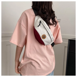 Rear view of a model wearing the white and burgundy canvas chest bag with adjustable strap